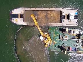 aerial view of excavator and barge dredging in the water